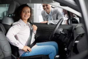 A woman sitting in car preparing for her driving lesson. Another women stands outside of the vehicle she might be her driving instructor and preparing for a driving lesson.