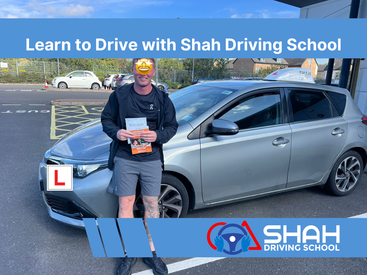 Learner driver celebrating after passing the driving test with Shah Driving School Bolton, standing beside a silver training car with L plates and Shah Driving School roof sign.