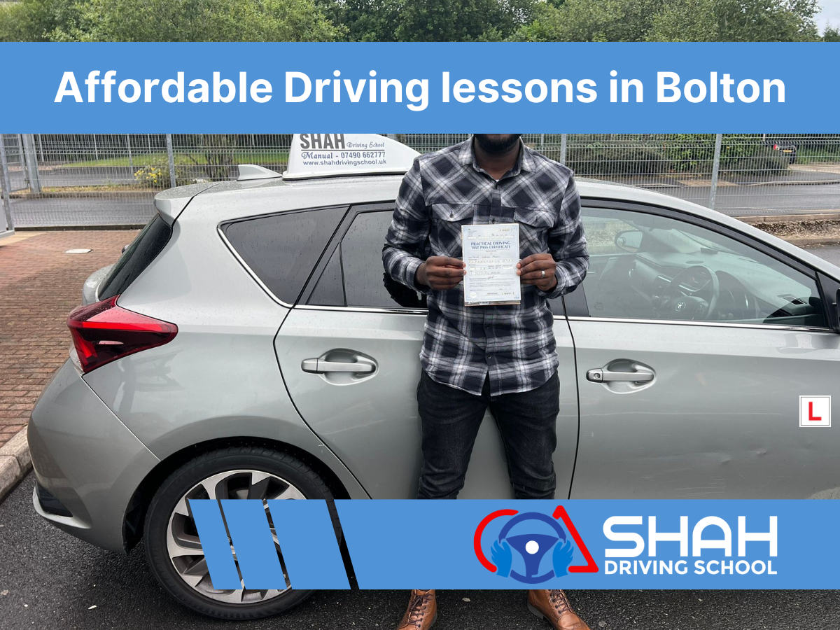 A Shah Driving School student proudly holding a driving test pass certificate beside a training car with a “L” sign, representing affordable driving lessons in Bolton.