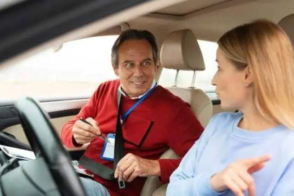 instructor teaching young lady driving